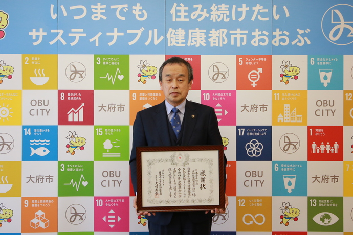 社資募集優秀地区表彰を手にする岡村市長